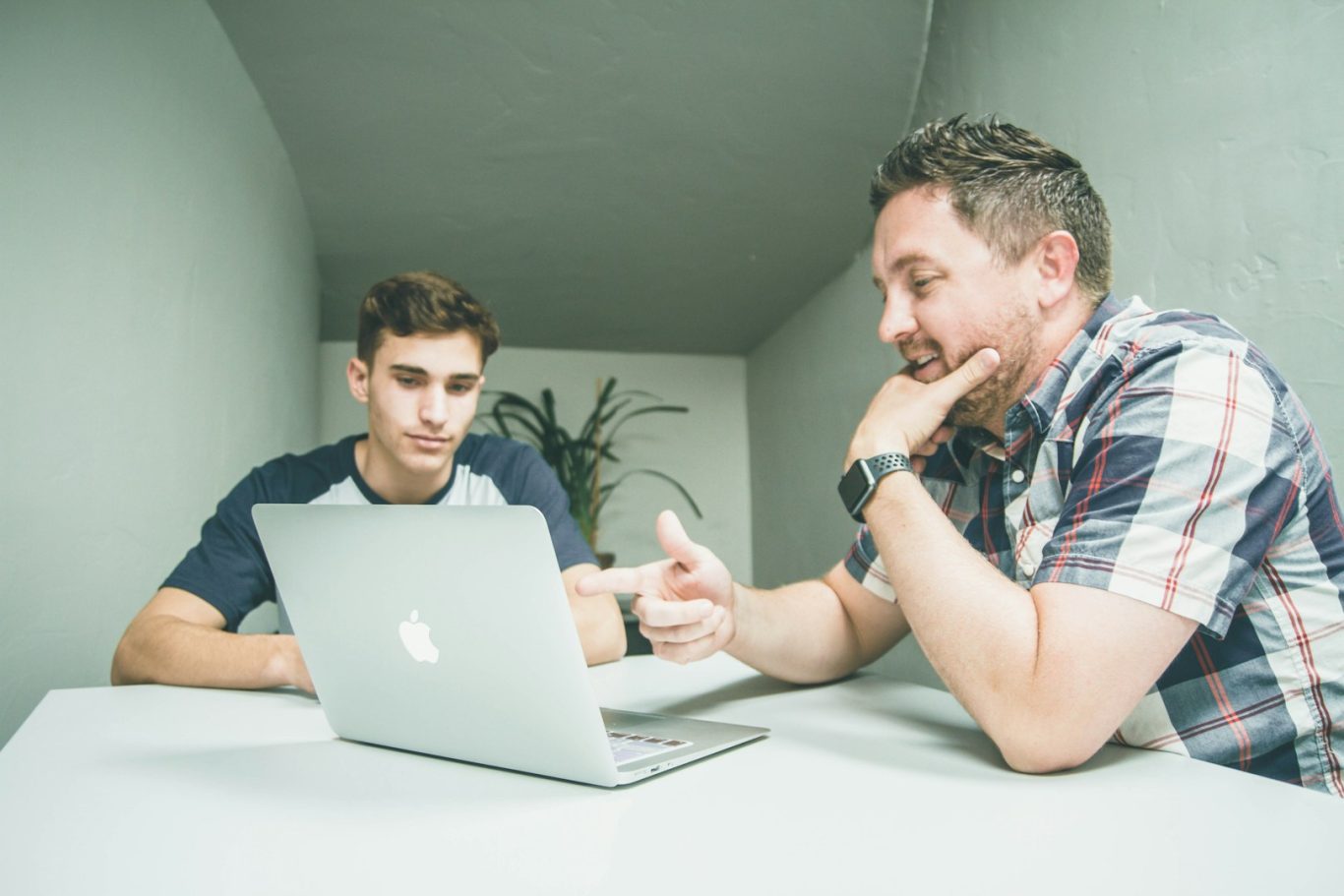 Betrachtung Ihrer individuellen Situation Zwei Menschen unterhalten sich und gucken auf einen Laptop.